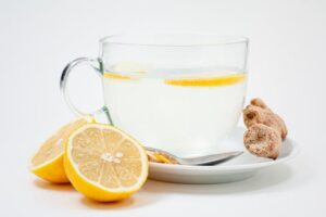 A soothing cup of lemon ginger tea with fresh lemon slices and ginger root on a white background.